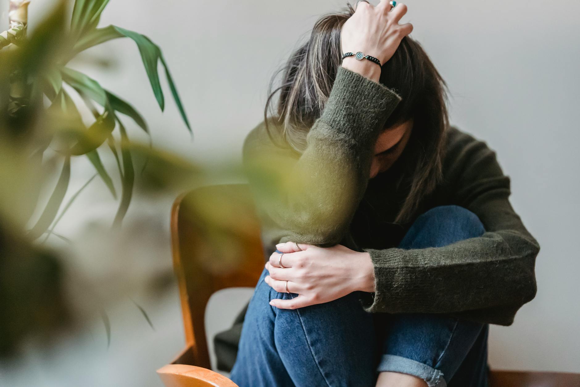 unrecognizable upset lady embracing knees sitting on chair