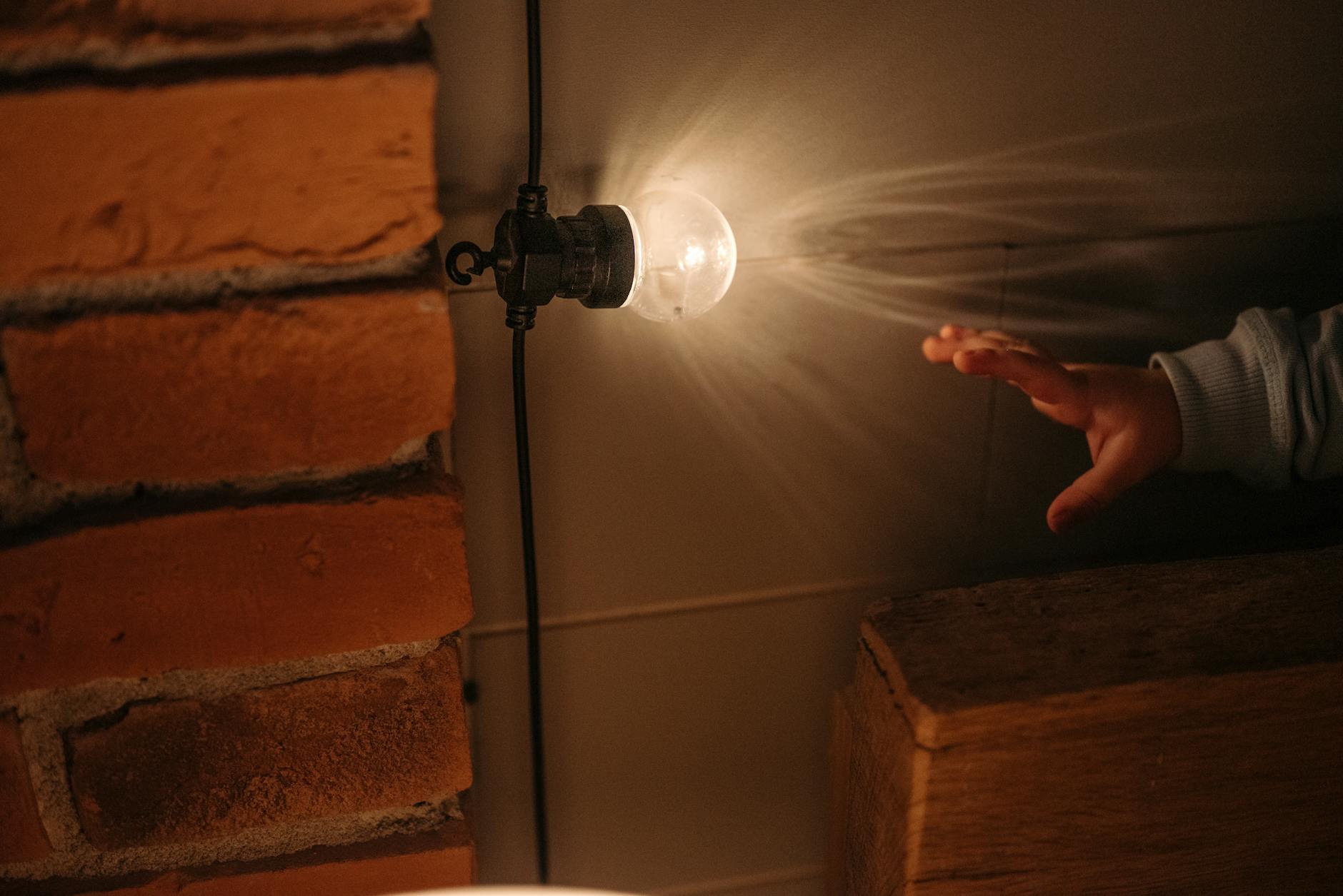 childs hand reaching for light bulb