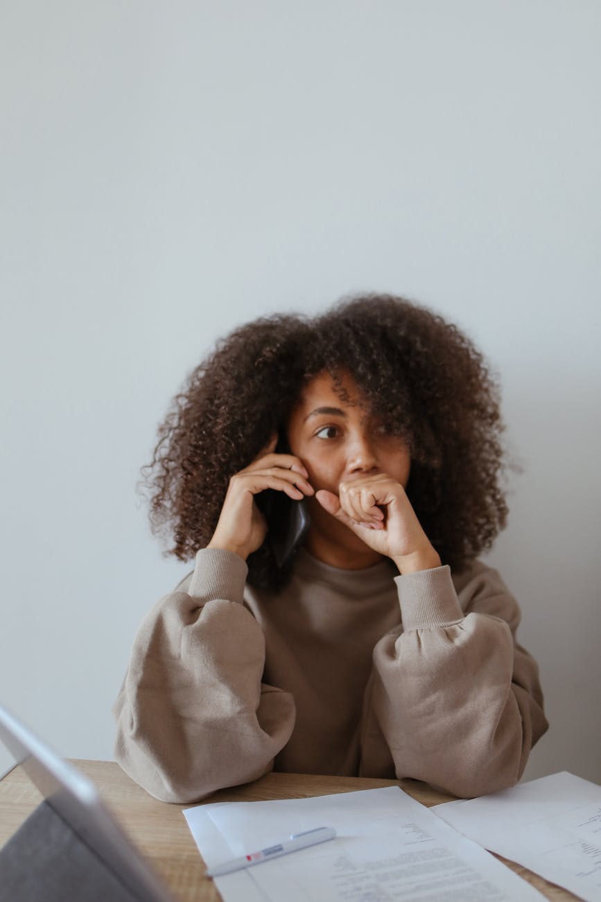 a woman wearing a brown sweater on a phone call